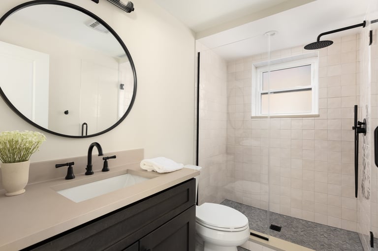 Cozy finished bathroom with dark wood cabinet brown quartz countertop walk-in shower with tan tiles and grey herringbone floor