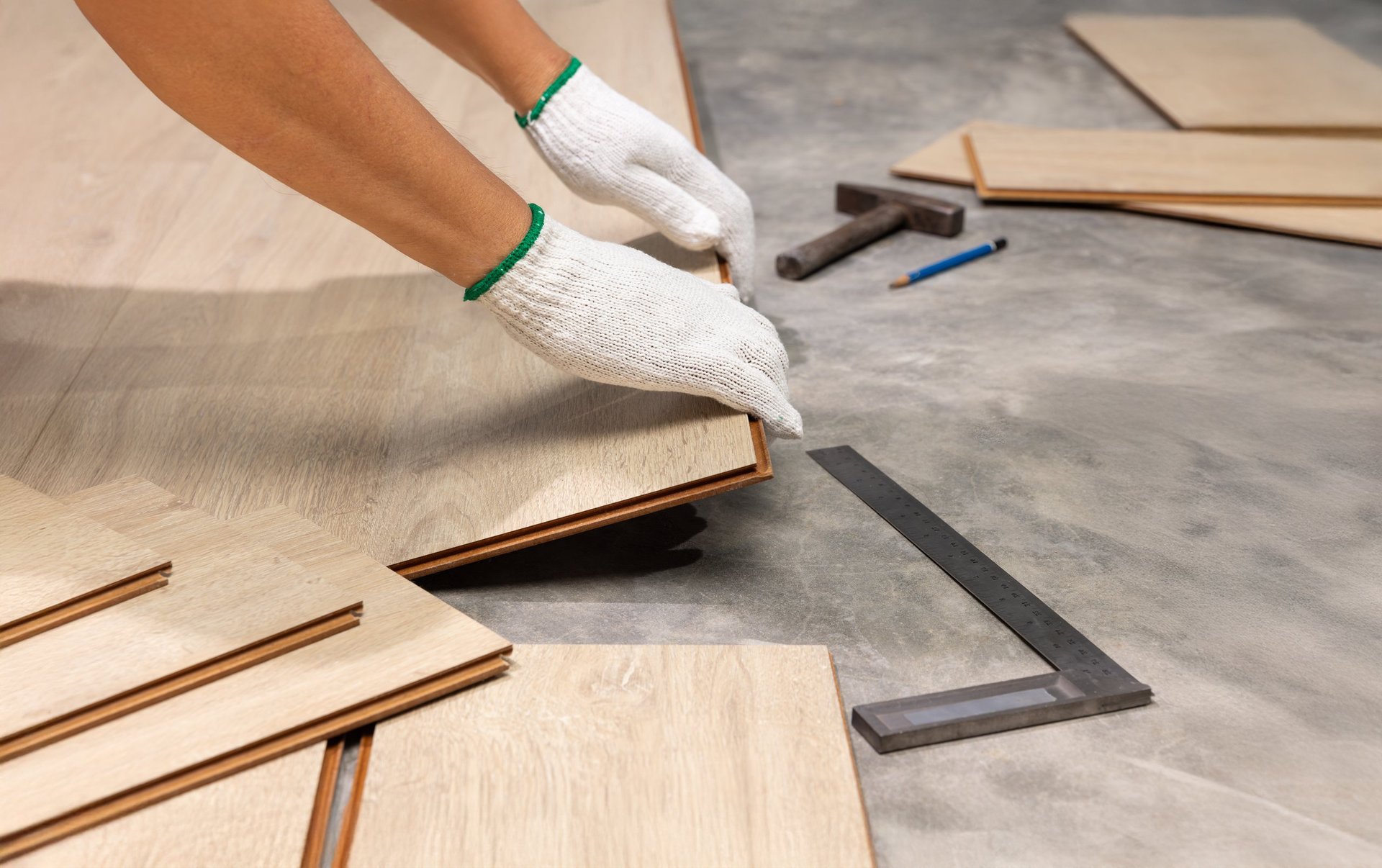 Worker installing interlocking laminate floor during home renovation project